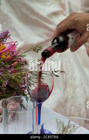 Rotwein, der bei einer Hochzeit aus einer Flasche in ein klares Weinglas gegossen wird, York, North Yorkshire, England, Großbritannien. Stockfoto
