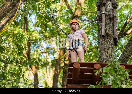 Mädchen in Hochseilen Erfahrung Abenteuer Baum Park. Seilbahnkurs in Bäumen. Kletterabenteuer Seilpark. Holzbrücke und hohe Drahtaktivität. Stockfoto