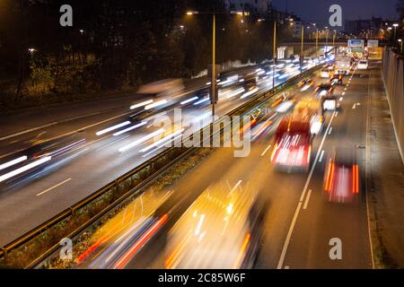 Der schnell fahrende Verkehr verläuft entlang einer deutschen Autobahn, die von der Münchner Innenstadt während der abendlichen Hauptverkehrszeit zum Flughafen führt. Stockfoto