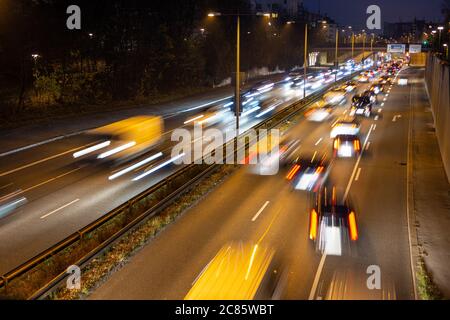 Der schnell fahrende Verkehr verläuft entlang einer deutschen Autobahn, die von der Münchner Innenstadt während der abendlichen Hauptverkehrszeit zum Flughafen führt. Stockfoto