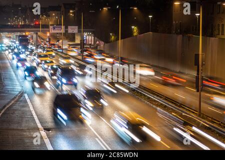 Der schnell fahrende Verkehr verläuft entlang einer deutschen Autobahn, die von der Münchner Innenstadt während der abendlichen Hauptverkehrszeit zum Flughafen führt. Stockfoto