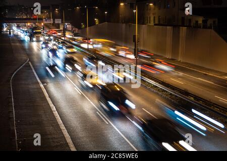 Der schnell fahrende Verkehr verläuft entlang einer deutschen Autobahn, die von der Münchner Innenstadt während der abendlichen Hauptverkehrszeit zum Flughafen führt. Stockfoto