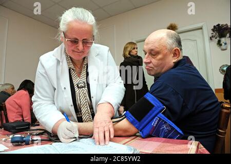 Sanitäter, der Blutdruck und Herzfrequenz mit Tonometer eines Patienten nimmt. Eröffnung des Pecherski Zentrums der sozialen Dienste. April 2018. Kiew, Ukra Stockfoto