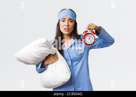 Besorgt und ängstlich Mädchen mit Panik als Alarm und halten Kissen, Aufwachen spät, verschlafen zur Untersuchung, nervös über weiß stehen Stockfoto