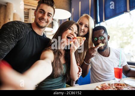 Fröhliche glückliche multirassische Freunde, die Selfie in der Pizzeria, während der Feier Urlaub Zeit beginnen. Stockfoto