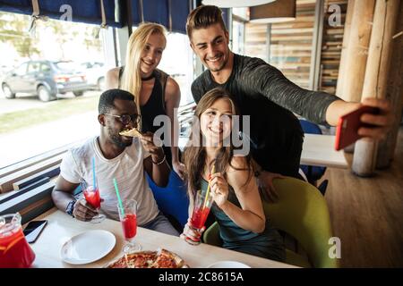 Fröhliche glückliche multirassische Freunde, die Selfie in der Pizzeria, während der Feier Urlaub Zeit beginnen. Stockfoto