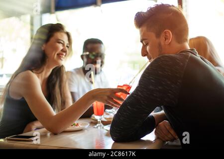 Glückliche multietnhische Freunde genießen Vorspeise in der amerikanischen Bar, jubelnde mit tropischen Früchten Cocktails, genießen Freizeit verbringen zusammen. Stockfoto