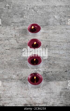 Kleine rote brennende Kerzen auf dem Betonboden, Draufsicht Stockfoto