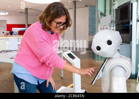 Eine Frau kommuniziert mit einem Roboter Berater Stockfoto