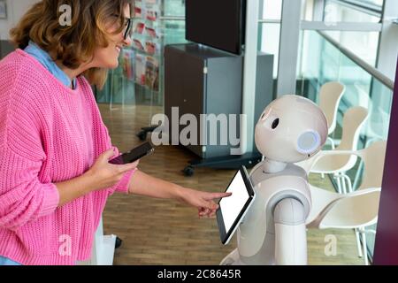 Eine Frau kommuniziert mit einem Roboter Berater Stockfoto