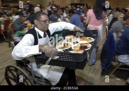 San Antonio, Texas USA, 24. November 2005: Ein afroamerikanischer Mann im Rollstuhl serviert beim jährlichen Raul Jiminez Thanksgiving Dinner, bei dem mehr als 25.000 Mahlzeiten am Thanksgiving Day für ältere Menschen, Obdachlose, Arme und Vertriebene aus Südtexas serviert werden. Die Veranstaltung, die vom verstorbenen Restaurantbesitzer Raul Jiminez ins Leben gerufen wurde, findet im 26. Jahr statt. ©Bob Daemmrich Stockfoto