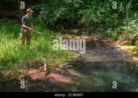 Junge Anfänger Jungen Angeln auf dem Flussufer Stockfoto