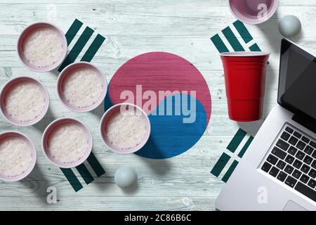 Südkorea Flagge Konzept mit Kunststoff Bier Pong Tassen und Laptop auf nationalen Holztisch, Draufsicht. Bier Pong Spiel. Stockfoto