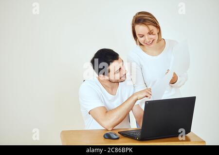 Glückliches junges Paar zu Hause, das Rechnungen mit Laptop bezahlt Stockfoto