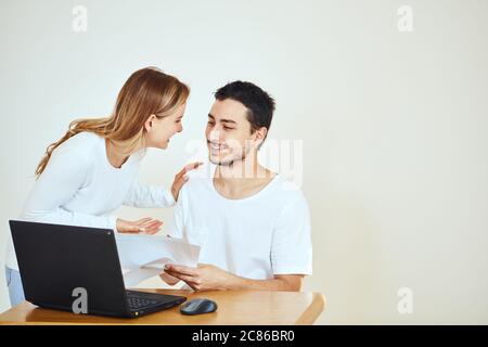 Glückliches junges Paar zu Hause, das Rechnungen mit Laptop bezahlt Stockfoto