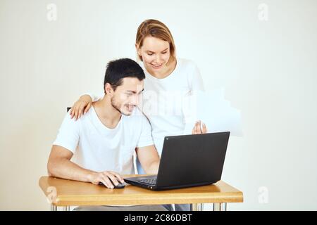 Glückliches junges Paar zu Hause, das Rechnungen mit Laptop bezahlt Stockfoto