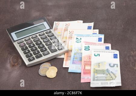 Banknoten und Münzen, die mit Taschenrechner. Euro-banknoten auf Holz- Hintergrund. Foto von Steuern, Gewinn und Kalkulation. 50 Euro, 20 Euro, 10 Euro. Geld und Fina Stockfoto