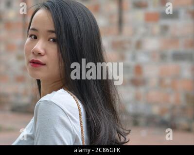 Hübsches vietnamesisches Mädchen geht weg und gibt einen letzten Blick über ihre Schulter. Stockfoto