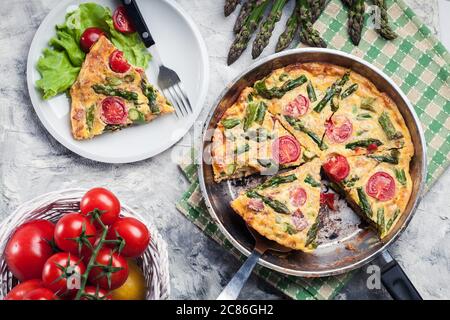 Frittata aus Eiern, Spargel und Kirschtomaten auf einer Pfanne. Italienische Küche Stockfoto