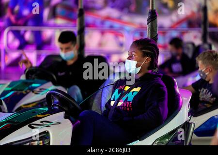 Dortmund, 21. Juli 2020: Mädchen mit Gesichtsmaske in einem Motorroller. Der temporäre Pop-up-Freizeitpark 'funDOmio' wurde am 25. Juni 2020 auf dem Messegelände rund um die Dortmunder Westfalenhalle eröffnet. Die Schausteller wollen die bitteren Verluste, die durch die koronabedingten Schließungen der Messen verursacht wurden, ein wenig kompensieren. Der Vergnügungspark ist bis zum 11. August 2020 geöffnet. Stockfoto