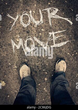 Motivationsposter mit Schriftzug 'Your Move'. Beine in Schuhen Draufsicht. Konzeptionelle schriftliche Botschaft für die Zukunft. Erste Person Ansicht der Stiefel Stockfoto