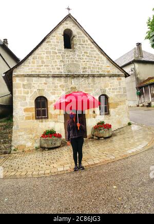 Foto aufgenommen in einem kleinen Dorf in Frankreich bei Regenwetter. Touristen schützen sich vor covid-19 auch während der Sommerferien Stockfoto