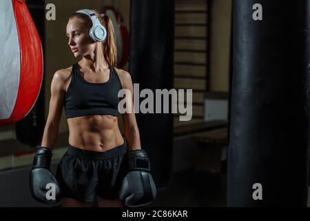 Blonde Mädchen in schwarzen Boxhandschuhe posiert im Fitnessstudio Stockfoto