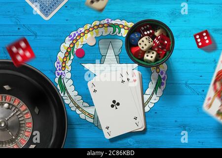 Nördliche Marianen Casino Thema. Asse im Pokerspiel, Karten und Chips auf rotem Tisch mit Nationalflagge Hintergrund. Glücksspiel und Wetten. Stockfoto