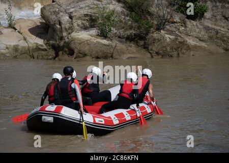 Im Sommer rudern die Teammitglieder im Rafting-Boot den Fluss hinunter. Extreme saisonale Outdoor-Sportarten sind eine gute Erholung optin Stockfoto