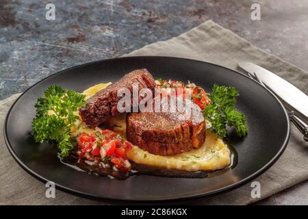 Rindermedaillons mit Tomatensalsa und Rahm Polenta Stockfoto