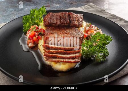 Rindermedaillons mit Tomatensalsa und Rahm Polenta Stockfoto