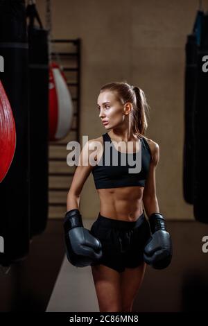 Blonde Mädchen in schwarzen Boxhandschuhe posiert im Fitnessstudio Stockfoto