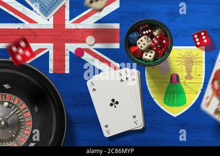 Turks und Caicos Inseln Casino Thema. Asse im Pokerspiel, Karten und Chips auf rotem Tisch mit Nationalflagge Hintergrund. Glücksspiel und Wetten. Stockfoto