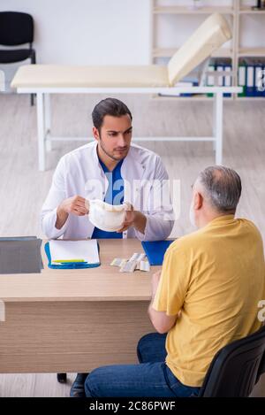 Alter Hals verletzten Mann besucht jungen Arzt Stockfoto