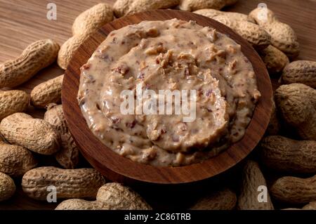 Amerikanisches Frühstück, süße Speisen und Snacks mit hohem Kalorien-Konzept mit einer Schüssel knackige Erdnussbutter von Erdnüssen noch in Schale, isoliert umgeben Stockfoto