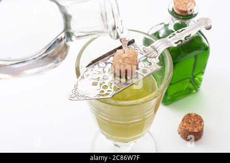 Alkohol, luxuriöse Spirituosen und gefährliche Spirituosen konzeptionelle Idee mit Kristallglas Absinth, gießen Wasser auf Edelstahl Löffel, Zuckerwürfel und Stockfoto