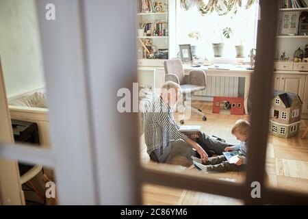 Großvater ergeht sich über seine Jugend, Fotoalbum, während sein Enkel spielen auf digital Tablet Stockfoto