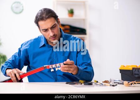 Junger Mann Reparatur der Gitarre Stockfoto