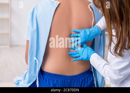 Junger verletzter Mann, der einen weiblichen Arzt aufsucht, Chiropraktiker Stockfoto