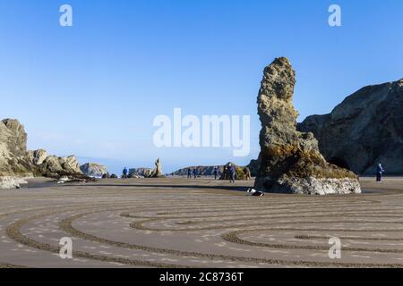 Bandon by the Sea, Oregon / USA - März 13 2020: Das Team von Kreisen im Sand Zeichnung ein begehbares Labyrinth am Strand mit der natürlichen r Stockfoto