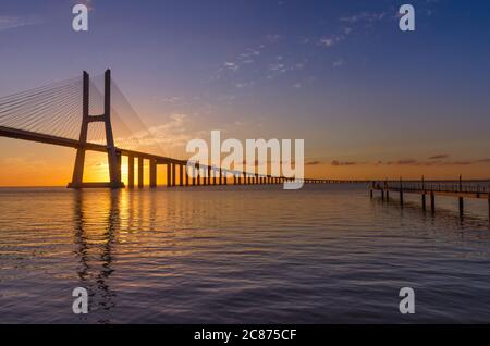 Sonnenaufgang über der Vasco da Gama Brücke, der längsten Brücke Europas, die den Tejo überspannt, in Lissabon, Portugal. Stockfoto