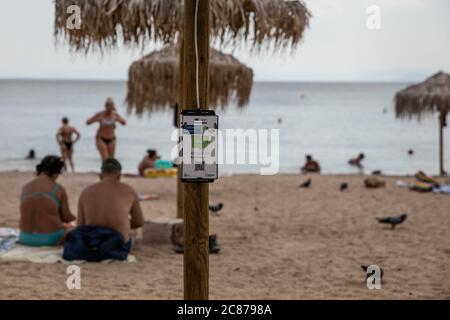 (200721) -- ATHEN, 21. Juli 2020 (Xinhua) -- das Foto vom 21. Juli 2020 zeigt ein Solarladegerät auf einem der Sonnenschirme an einem öffentlichen Strand in der Nähe des Rathauses der Gemeinde Vari-Voula-Vouliagmeni im Süden Athens, Griechenland. Ab Dienstag sind die Dutzende von Sonnenschirmen, die entlang des Strandes verteilt sind, gemäß den sicheren Entfernungsmaßnahmen zum Schutz gegen COVID-19, mit einem System aus Solarmodulen und USB-Anschlüssen ausgestattet, das kostenlos und umweltfreundlich aufgeladen werden kann. Im Rahmen eines am Dienstag gestarteten Pilotprogramms werden Sonnenanbeter zu Energiesparmaßnahmen beitragen Stockfoto