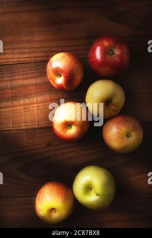 Das hohe Winkel Stillleben einer Gruppe frisch gepflückter Äpfel auf einem rustikalen Holztisch. Fuji, Gala, Granny Smith, Braeburn, Golden Delicious mit warmer Beilage l Stockfoto