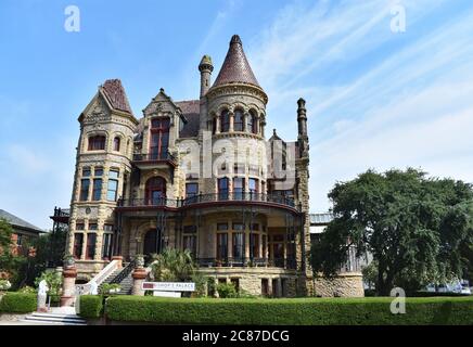 Der verzierte viktorianische Stil 1892 Bishops Palace in Galveston, Texas. Der Haupteingang zum Herrenhaus mit einem Willkommensschild für Besucher an der Hecke. Stockfoto