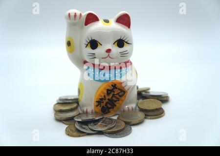 Japanische weiße Maneki Neko Glückliche Katzenbank Nahaufnahme mit Münzen Stockfoto