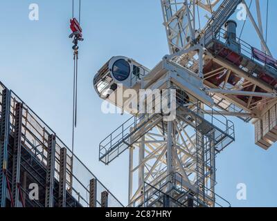 Betrieb eines Baukran, der Beton über einem unfertigen Gebäude hebt. Stockfoto