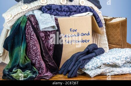 Vorgeliebte Kleidung in einer Box, die für Second Hand September markiert ist, wiederverwenden recyceln Kleidung durch Austausch für nachhaltige Mode und Null Abfall Stockfoto