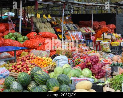 Frisches Obst und Gemüse Stallmarkt an der Straße in Land Kirgisistan bei Bischkek. Lokaler Anbieter mit orangefarbener Jacke in Zentralasien. Stockfoto