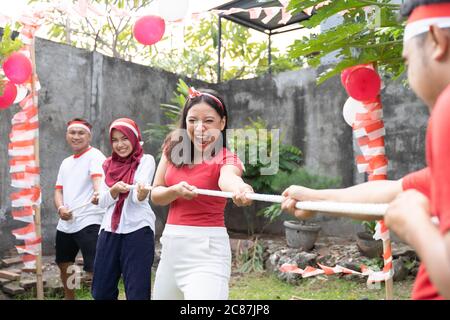 Drei Personen in einem Team versuchten, das Seil während des Tauziehen-Wettbewerbs auf Indonesiens Unabhängigkeitstag Feiern hart zu ziehen Stockfoto