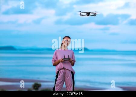 Nette Dame in rosa stilvolle Kleidung steuert die Drohne mit Fernbedienung. Stockfoto